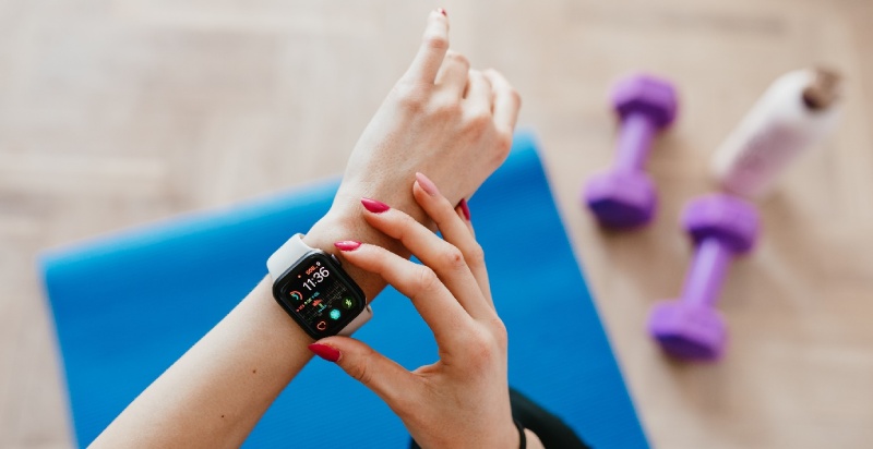 Woman adjusting smart watch whilst exercising