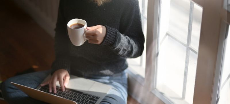 Woman drinking coffee and using a laptop